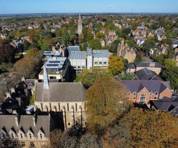 An aerial photograph of the St Antony's College campus. It is surrounded by leafy green trees.